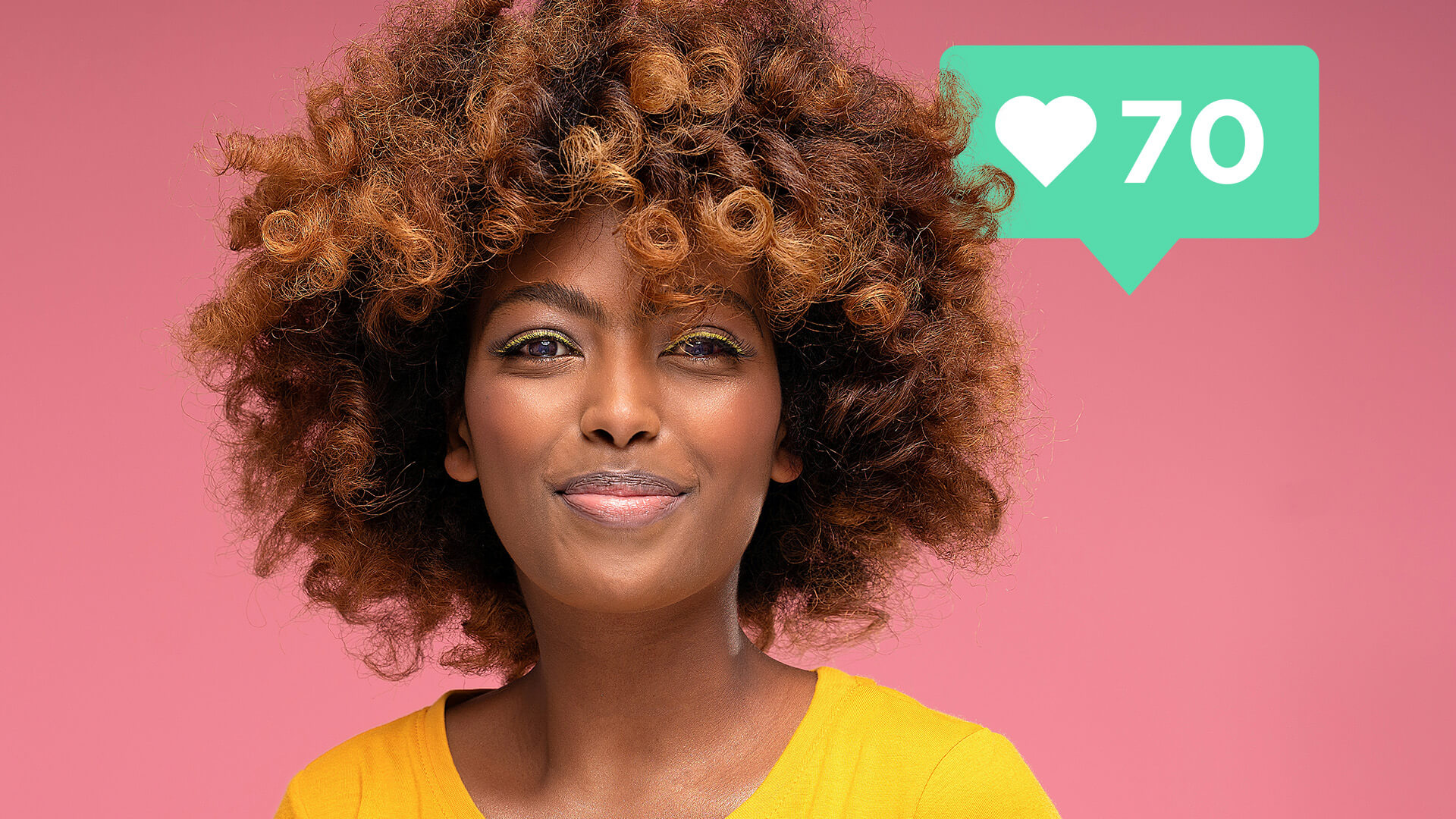A black beauty influencer poses, she wears a yellow top and has curly hair