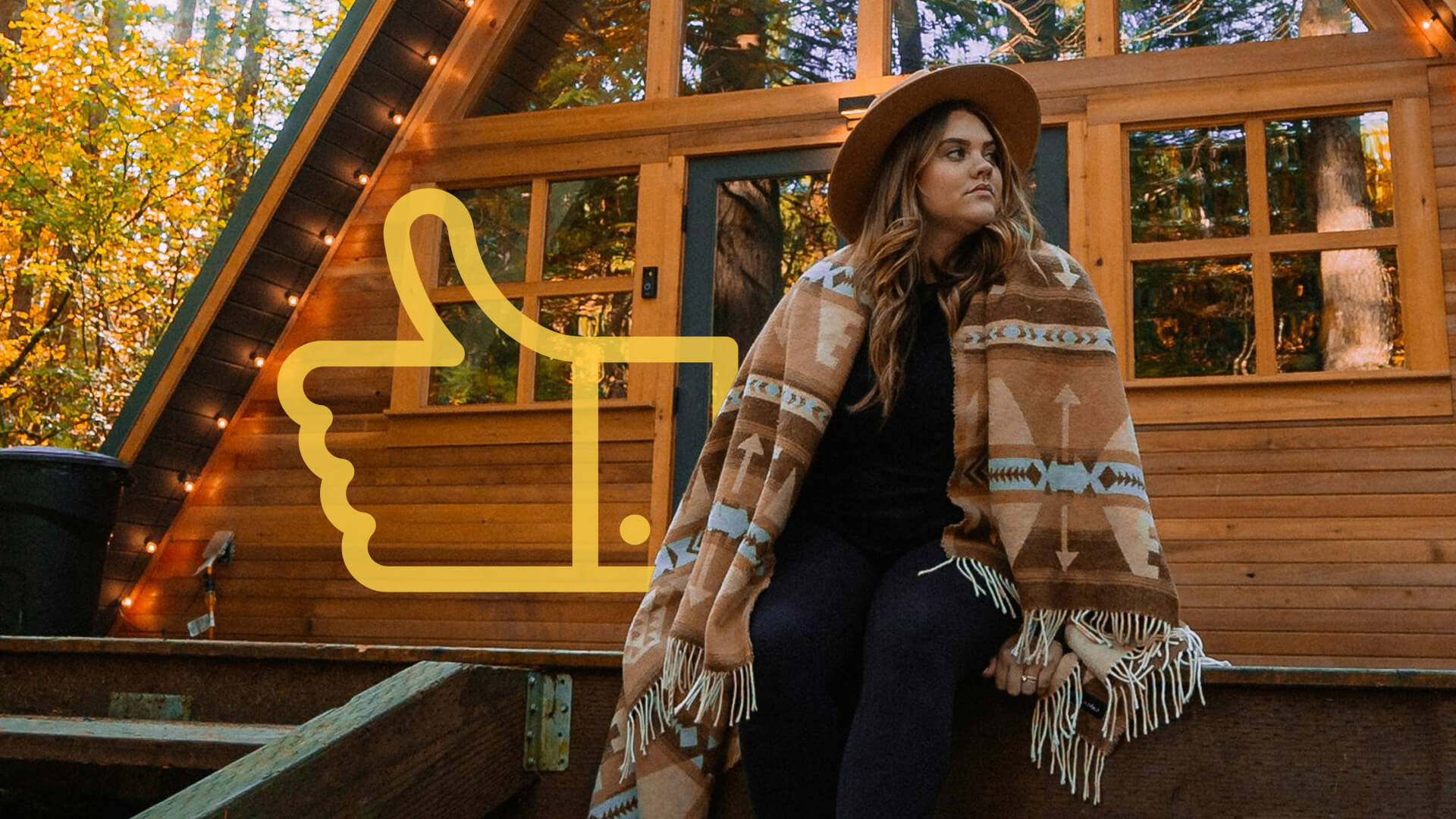A woman poses in front of a log cabin